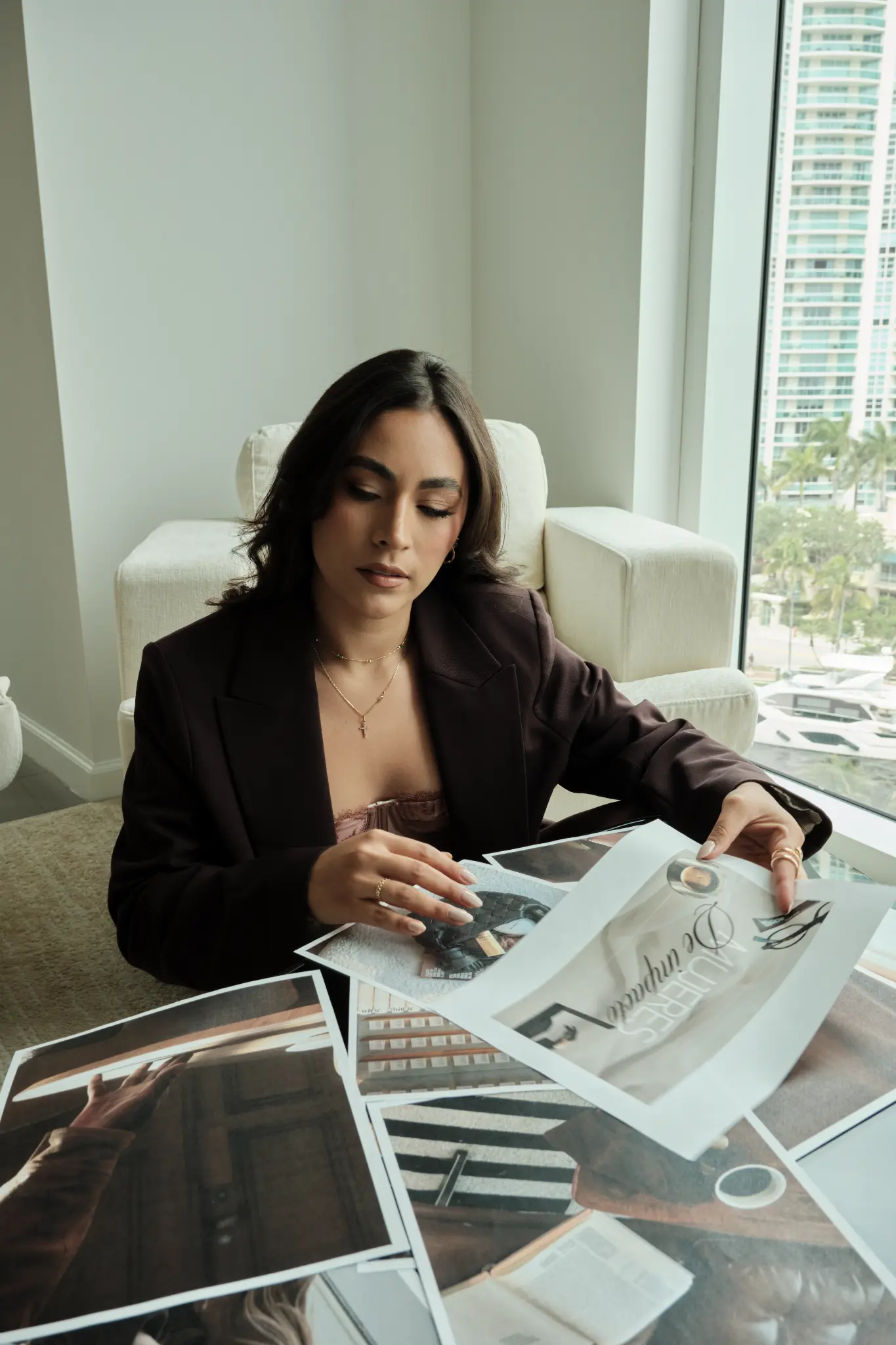 Catherine revisando impresos de marca en una mesa junto a una ventana